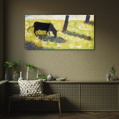 A cow grazing in a green landscape Glass art print
