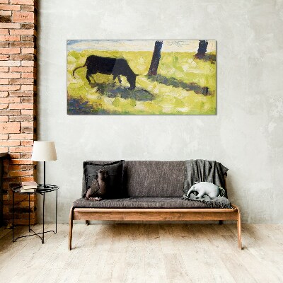 A cow grazing in a green landscape Glass art print