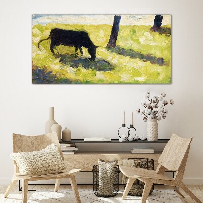 A cow grazing in a green landscape Glass art print