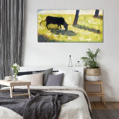 A cow grazing in a green landscape Glass art print